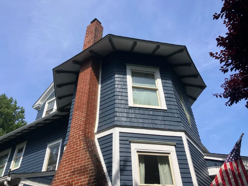 Blue home exterior with roofline, gutters, siding, chimney, and window trim